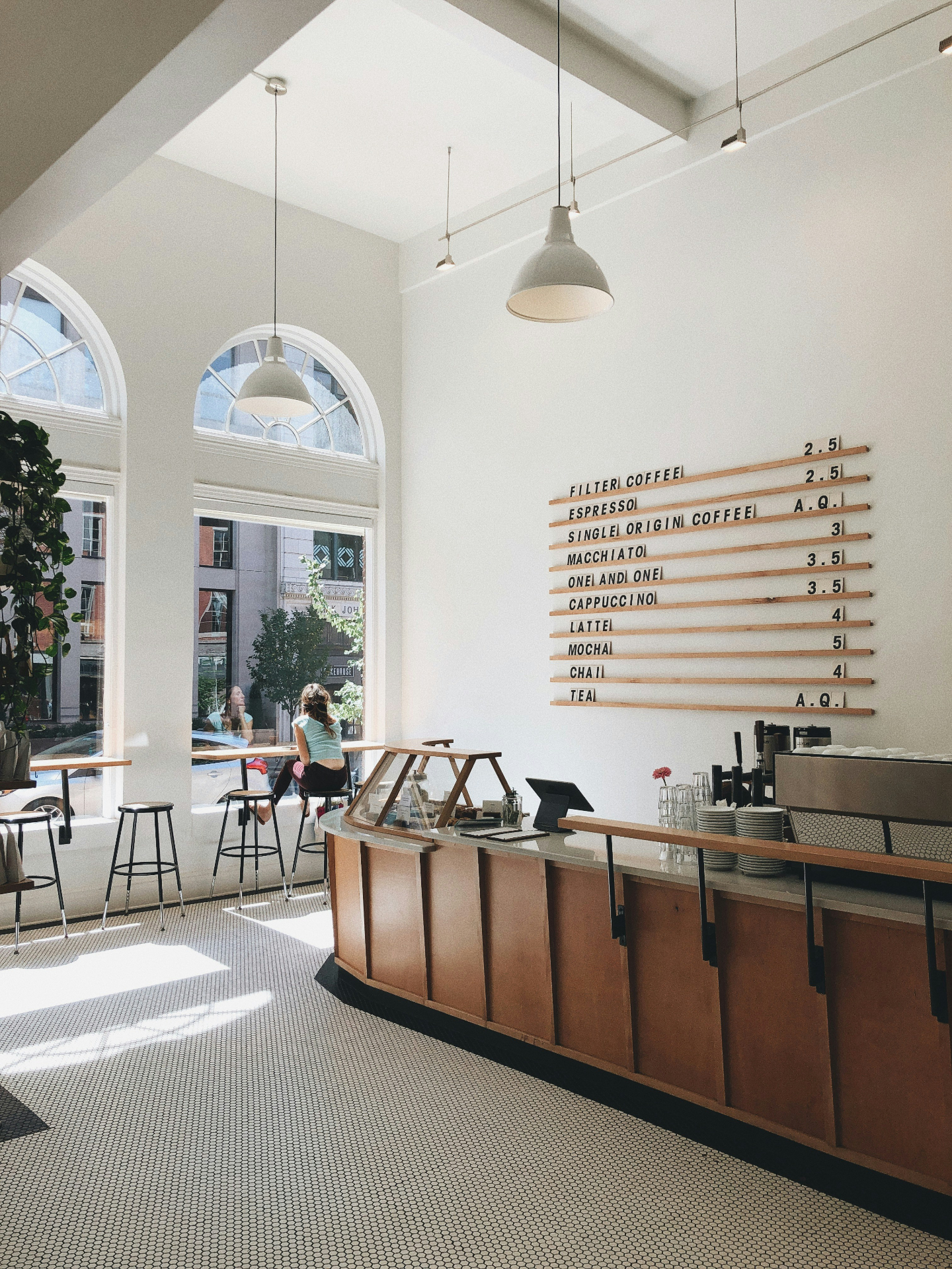 Bright cafe interior with arched windows and a wall-mounted menu